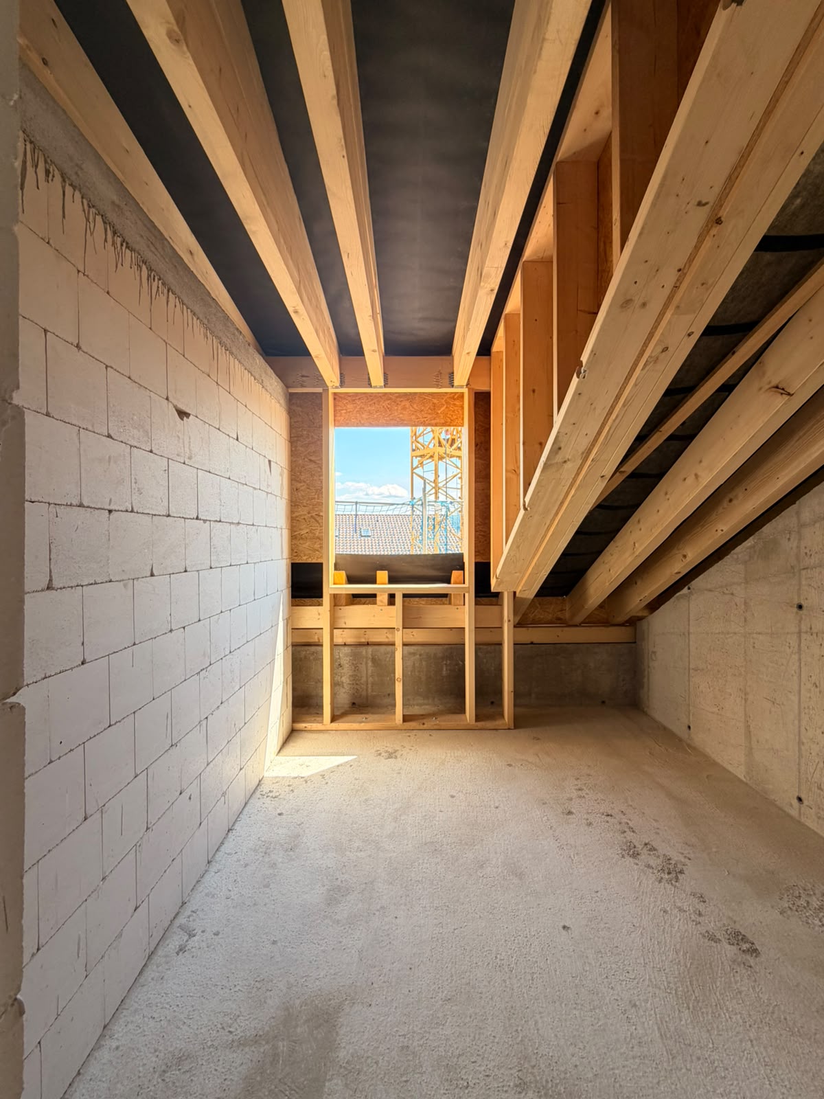 Dachgeschoss mit Holzsparren und sichtbarem Dachstuhl im Rohbau